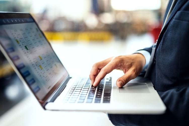 Homem de terno mexendo no computador.