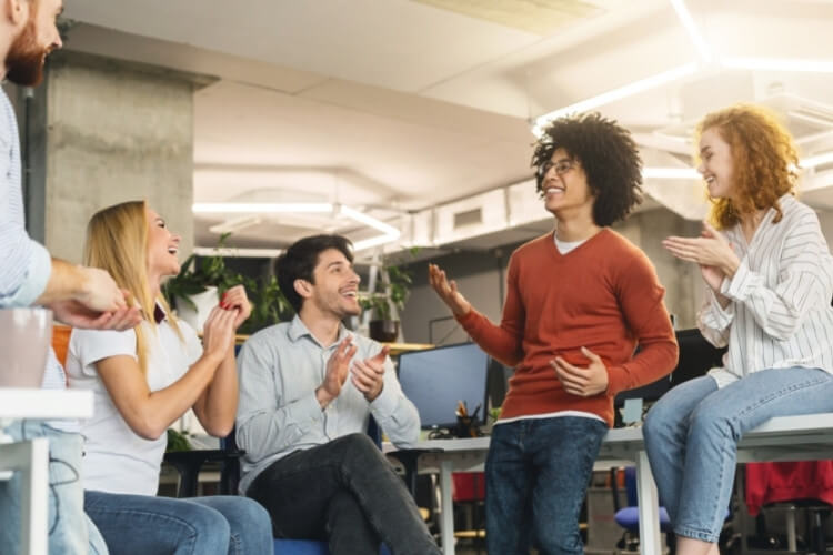 Equipe de trabalho diversa reunida, sorrindo e conversando.