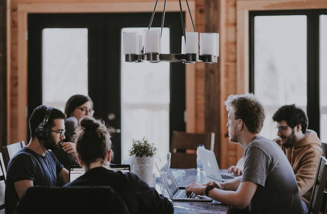 Equipe de trabalho ao redor de uma mesa, conversando.