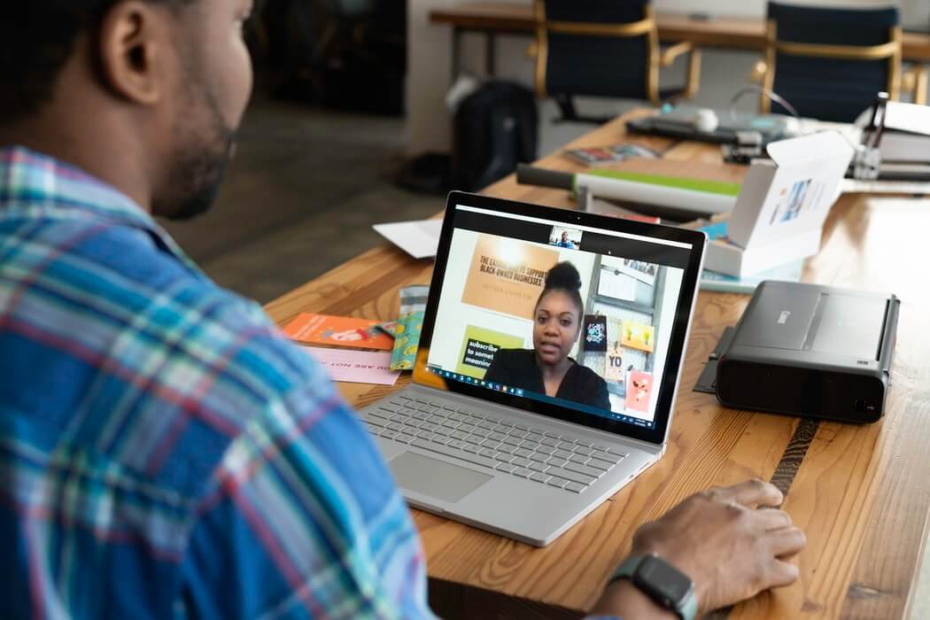 Homem negro fazendo curso com professora mulher pelo computador.