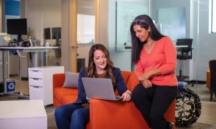 Mulheres de trabalho sentadas em frente ao computador, automatizando processos.